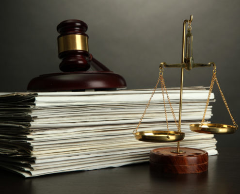 Golden scales of justice, gavel and books on grey background